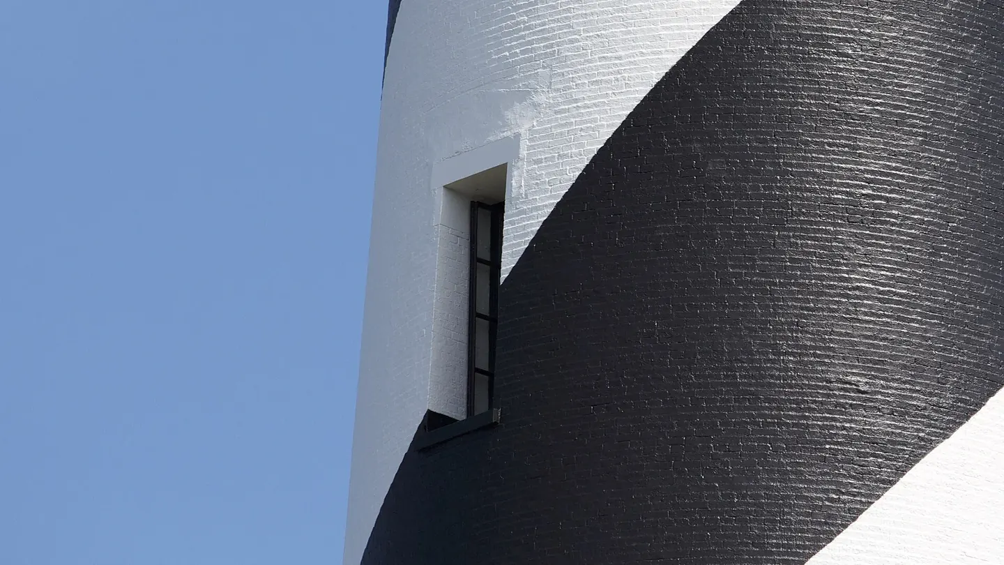The Cape Hatteras Lighthouse with its bold black and white spiral daymark rising above scrub and dunes at Buxton, North Carolina