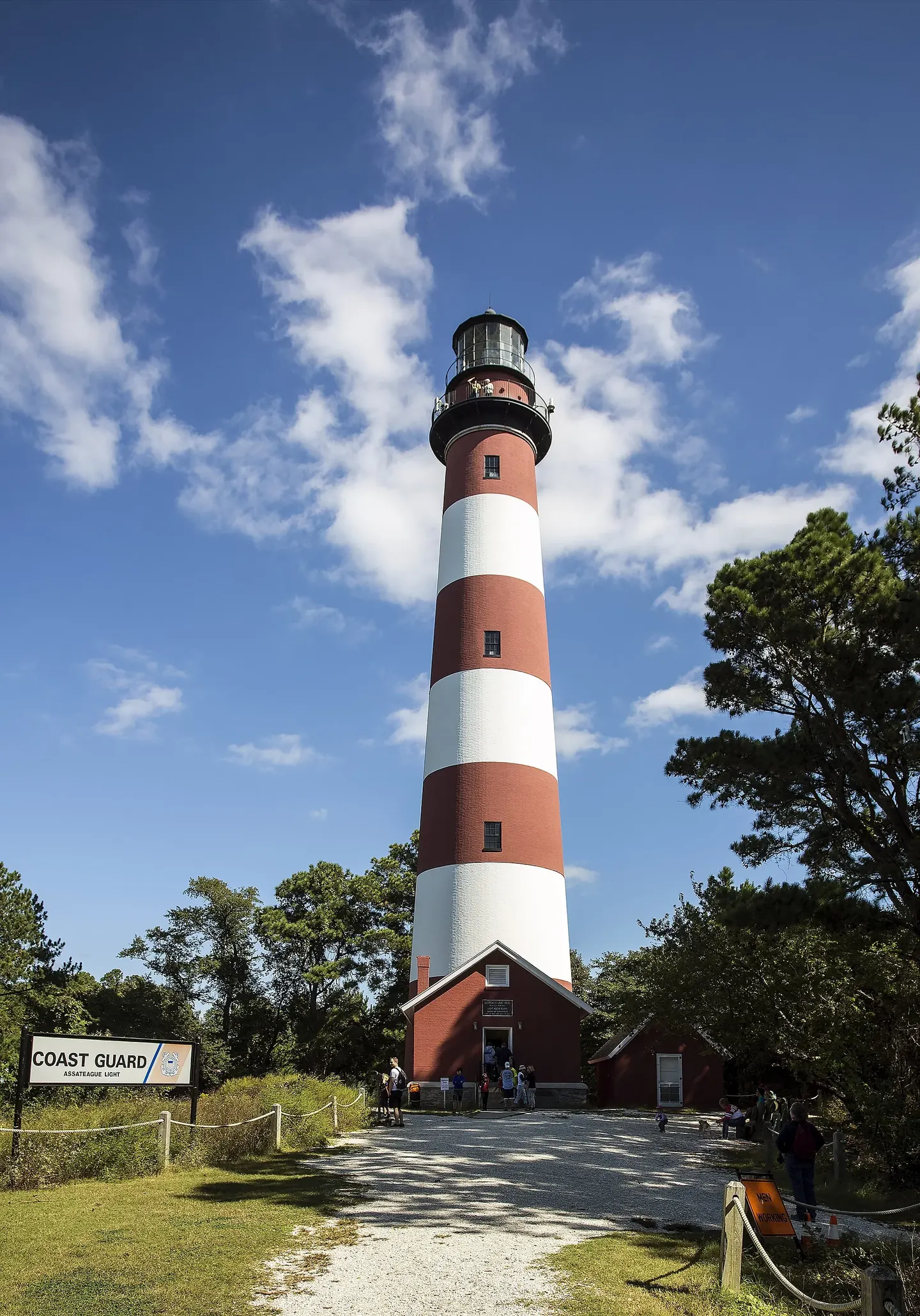 A lighthouse tower painted in bold black and white spiral stripes against a blue sky
